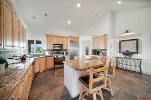 Kitchen with high vaulted ceiling, stainless steel appliances, light stone countertops, and tasteful backsplash