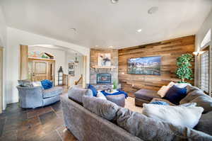 Living room featuring a stone fireplace and wood walls