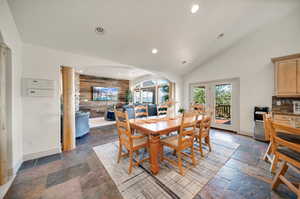 Dining room featuring wood walls and high vaulted ceiling