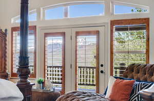 Primary Bedroom with multiple windows, French doors access to covered deck, mountain & lake views, and lofted ceiling