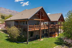 Back of property with a mountain view, a yard, and a hot tub