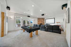 Playroom with french doors, a stone fireplace, billiards, theater room, and light carpet