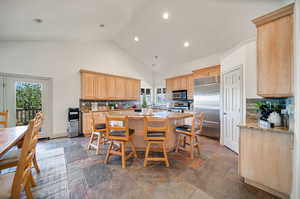 Kitchen with a wealth of natural light, light stone counters, appliances with stainless steel finishes, and a kitchen island