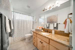 Full bathroom with tile patterned flooring, vanity, toilet, and shower / bath combo with shower curtain