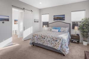 Carpeted bedroom featuring a barn door