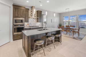 Kitchen with pendant lighting, a kitchen island with sink, stainless steel appliances, and sink