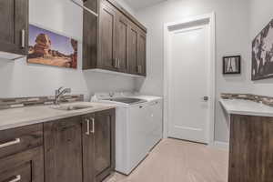 Washroom with washing machine and dryer, light tile patterned flooring, sink, and cabinets