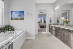 Bathroom featuring vanity, tile patterned flooring, ceiling fan, and a relaxing tiled tub