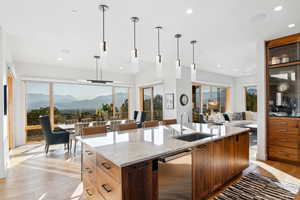 Kitchen featuring pendant lighting, a mountain view, a center island with sink, and light stone counters