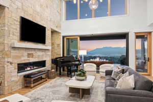 Living room with wood-type flooring, a stone fireplace, and a towering ceiling