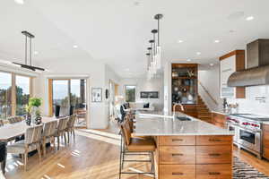 Kitchen with designer stove, a wealth of natural light, a large island with sink, and range hood