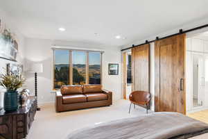 Bedroom with a barn door, light wood-type flooring, and a mountain view