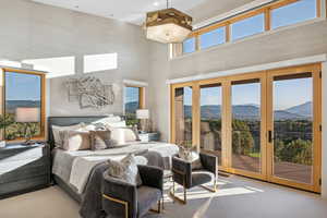 Carpeted bedroom with access to outside, a towering ceiling, a mountain view, and french doors