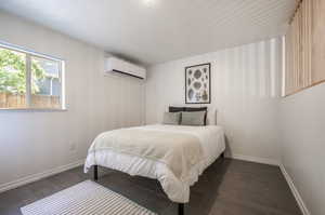 Bedroom with dark wood-type flooring and a wall mounted AC