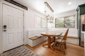 Dining space featuring an inviting chandelier, light hardwood / wood-style floors, and a textured ceiling