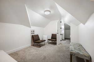 Sitting room featuring a textured ceiling, vaulted ceiling, and light colored carpet