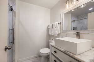 Bathroom with tiled shower, vanity, and toilet