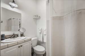 Bathroom with vanity, toilet, and curtained shower