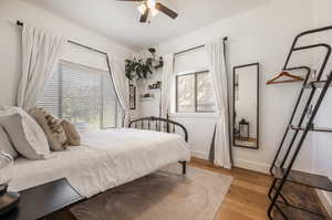 Bedroom with ceiling fan, light hardwood / wood-style flooring, and multiple windows