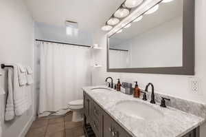 Bathroom with vanity, toilet, a shower with shower curtain, and tile patterned floors