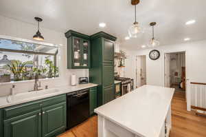 Kitchen featuring green cabinetry, dishwasher, light wood-type flooring, and gas stove