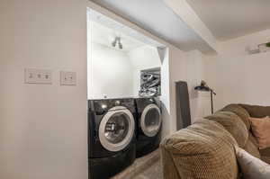 Washroom with washing machine and dryer and light colored carpet