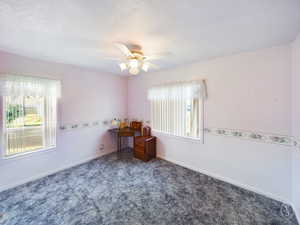 Carpeted empty room featuring a textured ceiling and ceiling fan