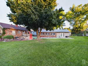 Back of house with a lawn and a patio