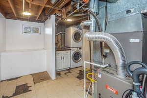 Clothes washing area featuring stacked washer and clothes dryer and cabinets