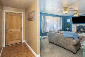 Interior space featuring ceiling fan, hardwood / wood-style flooring, a fireplace, and a textured ceiling