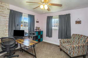 Office area featuring a textured ceiling, wooden walls, and ceiling fan