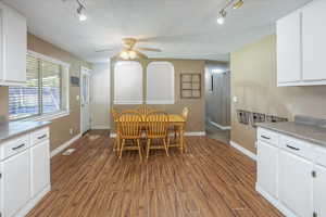 Dining space with a textured ceiling, rail lighting, ceiling fan, and dark hardwood / wood-style flooring