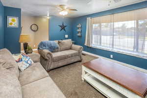 Carpeted living room with ceiling fan