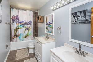 Full bathroom featuring wood-type flooring, vanity, shower / tub combo, and toilet