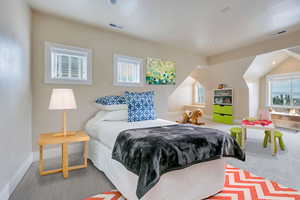 Bedroom with multiple windows, carpet flooring, and lofted ceiling