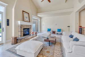 Tiled living room with high vaulted ceiling, ceiling fan, and a fireplace