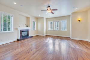 Spacious main floor master bedroom with hardwood floors and windows looking onto backyard