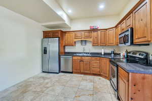 Apartment kitchen featuring dark stone countertops, appliances with stainless steel finishes, and sink