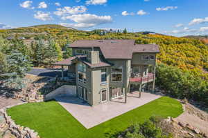 Rear view of property with a patio, a balcony, and a lawn