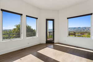 Empty room with a mountain view and dark hardwood / wood-style floors