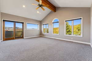 Carpeted empty room featuring beam ceiling, ceiling fan, high vaulted ceiling, and a mountain view