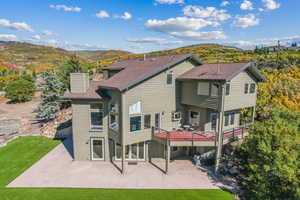 Rear view of house featuring a lawn, a patio area, and a deck with mountain view