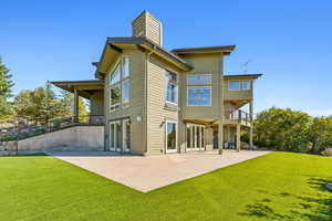 Rear view of property with a yard, a balcony, and a patio