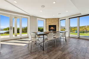 Dining room with dark hardwood / wood-style flooring, a stone fireplace, and a wealth of natural light