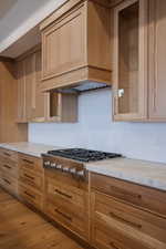 Kitchen with light hardwood / wood-style floors, stainless steel gas cooktop, light brown cabinets, and custom exhaust hood