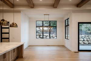 Unfurnished dining area with beamed ceiling, light hardwood / wood-style flooring, and a chandelier