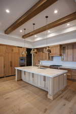 Kitchen featuring light wood-type flooring, beamed ceiling, a spacious island, and sink