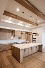 Kitchen with a spacious island, pendant lighting, sink, and light hardwood / wood-style floors