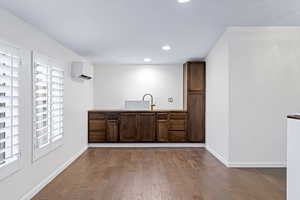 Interior space with light wood-type flooring, dark brown cabinetry, an AC wall unit, and sink