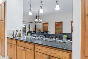 Kitchen featuring dark stone counters, hanging light fixtures, sink, and a notable chandelier